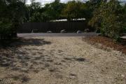 Photo: 010, JOHN PENNEKAMP CORAL REEF SP. View from campsite looking out toward road, opposite side of road with rocks, grass, trees, fence, and roof of residence.