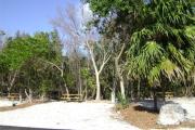 Photo: 012, JOHN PENNEKAMP CORAL REEF SP. Rock with campsite number, no shade gravel campsite with picnic table, grill, concrete sewer hookup basin, electric post, and paved road in foreground.