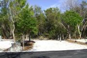 Photo: 014, JOHN PENNEKAMP CORAL REEF SP. Rock with campsite number, no shade gravel campsite with picnic table, grill, concrete sewer hookup basin, electric post, and paved road in foreground.