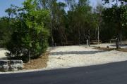 Photo: 015, JOHN PENNEKAMP CORAL REEF SP. Rock with campsite number, relatively no shade gravel campsite with picnic table, grill, concrete sewer hookup basin, electric post, and paved road in foreground.