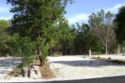 Photo: 017, JOHN PENNEKAMP CORAL REEF SP. Rock with campsite number, relatively no shade gravel campsite with picnic table, grill, concrete sewer hookup basin, electric post, and paved road in foreground.
