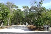 Photo: 019, JOHN PENNEKAMP CORAL REEF SP. Rock with campsite number, partially shaded gravel campsite with picnic table, grill, concrete sewer hookup basin, electric post, and paved road in foreground.