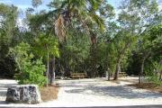 Photo: 021, JOHN PENNEKAMP CORAL REEF SP. Rock with campsite number, partially shaded gravel campsite with picnic table, grill, concrete sewer hookup basin, electric post, and paved road in foreground.