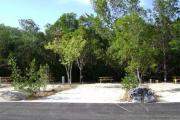 Photo: 024, JOHN PENNEKAMP CORAL REEF SP. Rock with campsite number, almost no shade gravel campsite with picnic table, grill, concrete sewer hookup basin, electric post, and paved road in foreground.