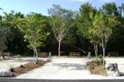 Photo: 026, JOHN PENNEKAMP CORAL REEF SP. Rock with campsite number, almost no shade gravel campsite with picnic table, grill, concrete sewer hookup basin, electric post, and paved road in foreground.