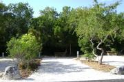 Photo: 029, JOHN PENNEKAMP CORAL REEF SP. Rock with campsite number, almost no shade gravel campsite with picnic table, grill, concrete sewer hookup basin, electric post, and paved road in foreground.