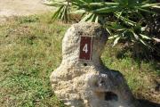 Large rock with metal sign with campsite number 4 on it located to the right of the site. Vegetation in the background.