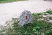 Large rock with metal sign with campsite number 14 on it located to the right of the site. Ground cover around rock.