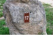 Large rock with metal sign with campsite number 17 on it located to the left of the site. Ground cover around rock.