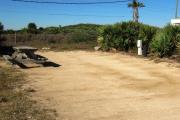Packed sand campsite with palmetto plants along the right side. Picnic table and ground grill off to the left of the campsite. Electric and water hookups located to the right of the campsite. Large palmetto plants provide privacy from adjacent site.