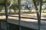 View of the back porch of a block cabin. A picnic table and fire ring is in the foreground. A beautiful blue lake is seen in the background just beyond a line of trees.