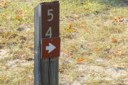 Close up of a brown site marker with an arrow on a wooden post.