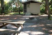 Cabin with picnic table and ground grill.