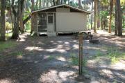 Cabin with picnic table and ground grill and water spigot.