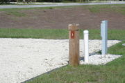 Photo: 001, Site number next to water and electric hooks ups at the back of a gravel site.