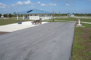 Photo: 009, ADA-accessible campsite with picnic table, grill and fire ring on the left and water and electric on the left. A paved sidewalk leads to the restroom.