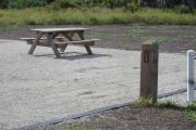 Site number next to water and electric hook ups at the back of a gravel site.