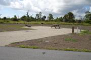 Campsite with picnic table, grill and fire ring on the left and water and electric on the right.