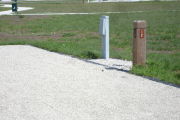 Photo: 012, Site number next to water and electric hooks ups at the back of a gravel site.