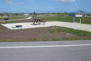 Photo: 012, Campsite with picnic table, grill and fire ring on the left and water and electric on the left. A restroom is nearby.