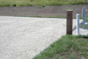 Photo: 013, Site number next to water and electric hooks ups at the back of a gravel site.