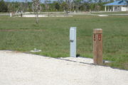 Photo: 016, Site number next to water and electric hooks ups at the back of a gravel site.