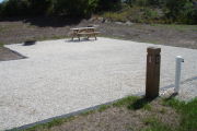 Photo: 020, Site number next to water and electric hooks ups at the back of a gravel site. Picnic table, grill and ground grill are to the left.
