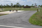 Photo: 021, ADA-accessible campsite with picnic table, grill and fire ring on the left and water and electric on the left.