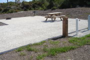 Photo: 022, Site number next to water and electric hooks ups at the back of a gravel site. Picnic table, grill and fire ring are to the left.