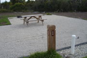 Photo: 024, Site number next to water and electric hooks ups at the back of a gravel site.