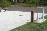 Photo: 025, Site number next to water and electric hooks ups at the back of a gravel site. A picnic table can be seen to the left.