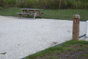 Photo: 028, Site number next to water and electric hooks ups at the back of a gravel site.
