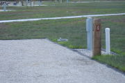 Photo: 029, Site number next to water and electric hooks ups at the back of a gravel site.