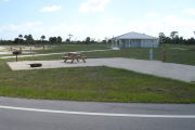 Photo: 029, Campsite with picnic table, grill and fire ring on the left and water and electric on the left. A restroom is nearby.