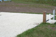 Photo: 030, Site number next to water and electric hooks ups at the back of a gravel site.