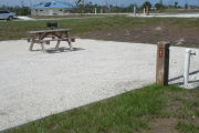 Photo: 031, Site number next to water and electric hooks ups at the back of a gravel site. Picnic table and grill are seen to the left.
