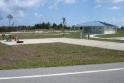 Photo: 034, Campsite with picnic table, grill and fire ring on the left and water and electric on the left. A restroom is nearby.