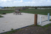 Photo: 035, Site number next to water and electric hooks ups at the back of a gravel site. A picnic table, grill and fire ring can be seen on the left.