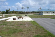 Photo: 036, ADA-accessible campsite with picnic table, grill and fire ring on the left and water and electric on the left. A paved sidewalk leads to a nearby restroom.