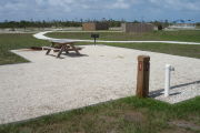 Photo: 037, Site number next to water and electric hooks ups at the back of a gravel site. A picnic table, grill and fire ring can be seen to the left.