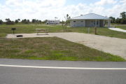 Photo: 042, Campsite with picnic table, grill and fire ring on the left and water and electric on the left. A restroom is nearby.