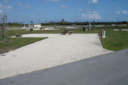 Photo: 043, Campsite with picnic table, grill and fire ring on the left and water and electric on the left. A restroom is nearby.