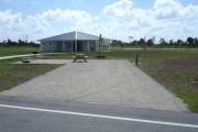 Photo: 044, Campsite with picnic table, grill and fire ring on the left and water and electric on the left. A restroom is nearby.