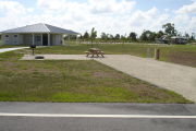 Photo: 044, Campsite with picnic table, grill and fire ring on the left and water and electric on the left. A restroom is nearby.