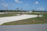 Photo: 045, Campsite with picnic table, grill and fire ring on the left and water and electric on the left. A restroom is nearby.