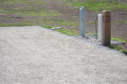 Photo: 046, Site number next to water and electric hooks ups at the back of a gravel site.