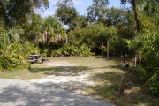 Picnic table and clothes posts at edge of site surrounded by green trees and grass.