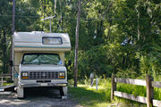A small recreational vehicle sits neatly on campsite number ten, adjacent to dense green vegetation and utility hook-ups, at Lake Griffin State Park