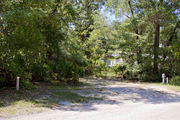 Bright sunlight filters through the dense green oak tree canopy, decorating the dirt and gravel pad on campsite number twenty-six at Lake Griffin State Park