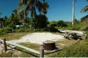 Photo: 006, From the Ocean side looking over the fence rails toward the camp road, the fire ring is on the lower right with the picnic table just beyond it. A Palm tree is between this and the next site along with other vegetation.